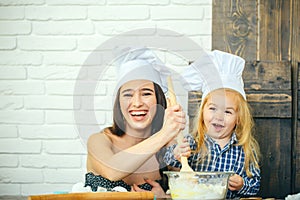 Woman and child boy smiling in chef hats with spoon