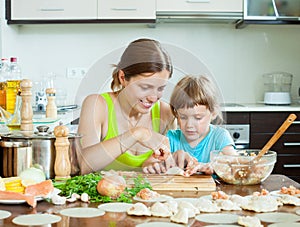 Woman with child cooking fish pelmeni (pelmeni), always together