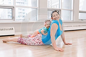Woman with child daughter doing workout in gym class to loose baby weight