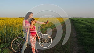 Woman with a child doing selfie in nature. A happy mother with her daughter is photographed in the countryside. Cyclists