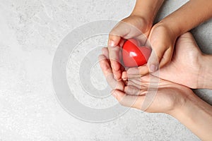 Woman and child holding heart on grey stone background. Donation concept