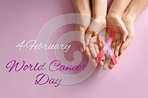 Woman and child holding pink ribbon on background, top view. World Cancer Day
