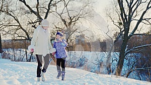 A woman with a child laughing in a winter park. Girl runs about mom and enjoys a good winter day