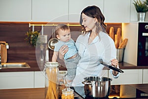 Woman with child opening saucepan on stove
