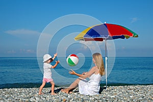 Woman and child play a ball at coast