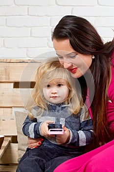Woman and child play on cell phone.