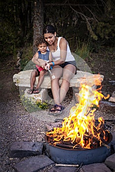 Woman and child roasting marshmallows over a campfire