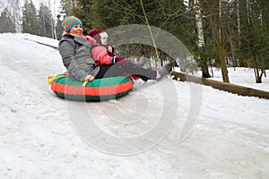 Woman with child rolling hills on a sledge in the photo
