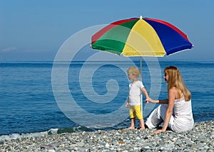 Woman and child sit under an umbrella