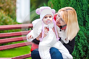 Woman with a child sitting on a park bench.