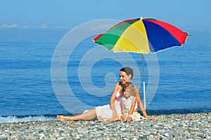 Woman and child sitting under an umbrella