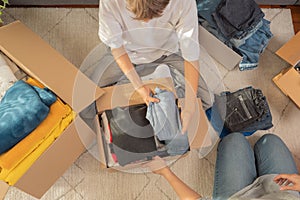 Woman and child sorting clothes and packing into cardboard box. Donations for charity, help low income families