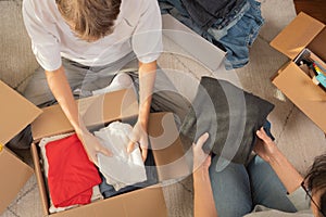 Woman and child sorting clothes and packing into cardboard box. Donations for charity, help low income families