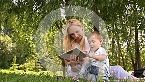 Woman and child using tablet computer. Slow motion. Young mother and little son spending day in the park.