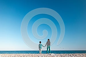 A woman with a child walks along the sea coast