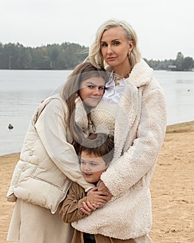 Woman child walks beach cold weather, mom with son and daughter in light clothes. Have fun together. Concept of tenderness, love,