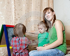 Woman and children draws on blackboard