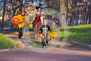 Woman with children run in Halloween costumes and scary pumpkin