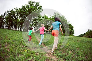 A woman with children runs along the grass.