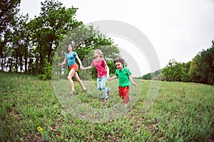 A woman with children runs along the grass.