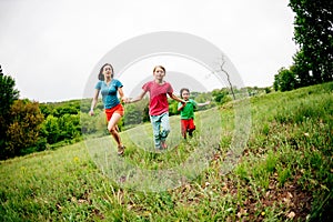 A woman with children runs along the grass.