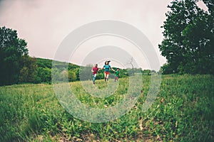 A woman with children runs along the grass.