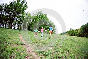 A woman with children runs along the grass.