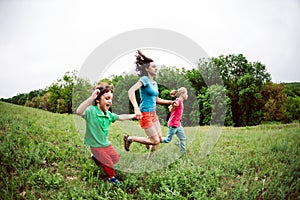 A woman with children runs along the grass.