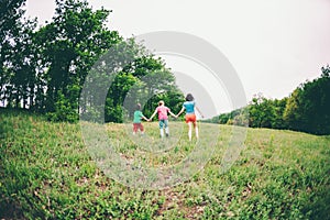 A woman with children runs along the grass.