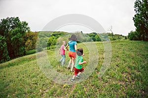 A woman with children runs along the grass.