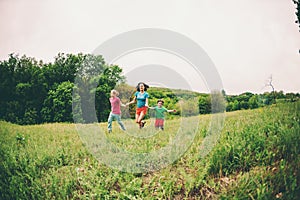 A woman with children runs along the grass.