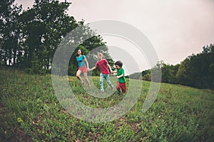 A woman with children runs along the grass.