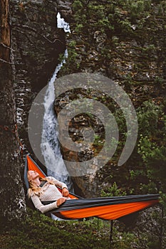 Woman chilling in hammock in forest outdoor camping gear summer vacations girl enjoying waterfall view in Norway