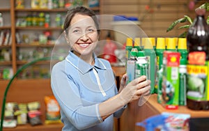 Woman chooses agricultural chemicals at shop for gardeners