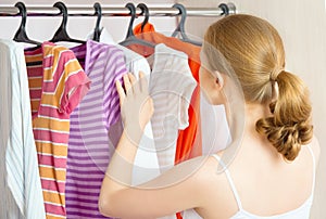 Woman chooses clothes in the wardrobe closet at home