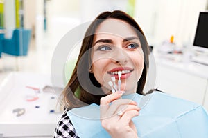 Girl chooses color of veneers at the dentist office photo
