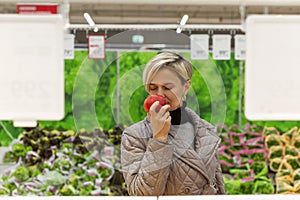 A woman chooses a red bell pepper in a supermarket. Healthy food and vegetarianism