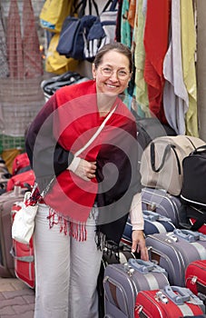 Woman chooses suitcase at shop