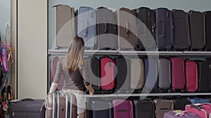 Woman chooses suitcase at shop