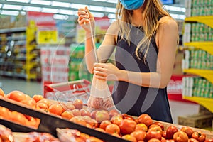 A woman chooses tomatoes in a supermarket without using a plastic bag. Reusable bag for buying vegetables. Zero waste