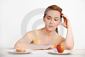 Woman Choosing Between Apple And Doughnut For Snack