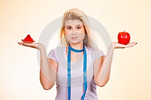 Woman choosing between apple and sweet cupcake