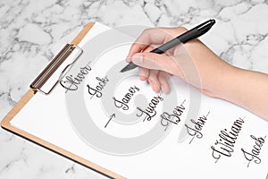 Woman choosing baby name at white marble table, closeup