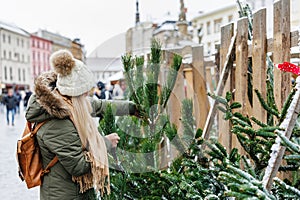 Woman is choosing and buying Christmas tree at fair market in city
