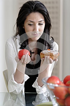 Woman choosing cake or fruit