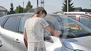 Woman choosing car for buying in dealership really desiring