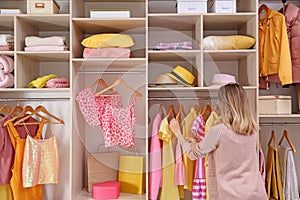 Woman choosing clothes from large wardrobe