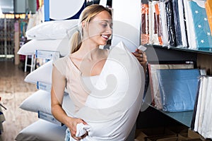 Woman choosing downy pillow in textile store