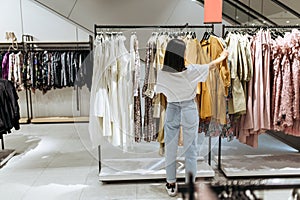 Woman choosing elegant dress in clothing store