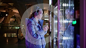 Woman choosing food automat standing in subway close up. Girl buying snacks.